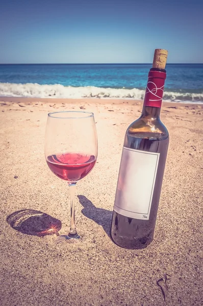 A bottle of wine and glass on the beach - retro and vintage styl