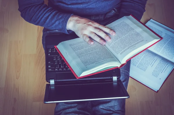 Young man sitting on the floor in living room and reading a book