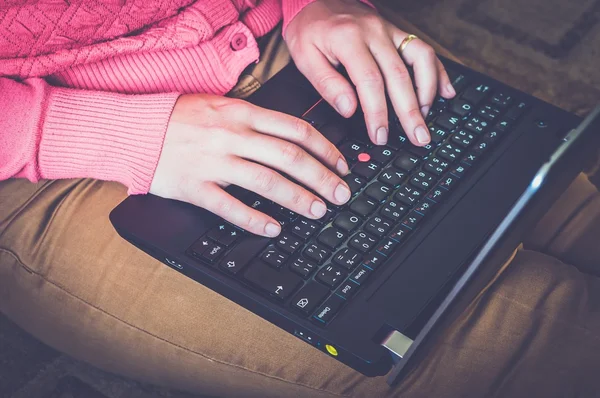 Young woman using a laptop and sitting on the floor in a living room — Φωτογραφία Αρχείου