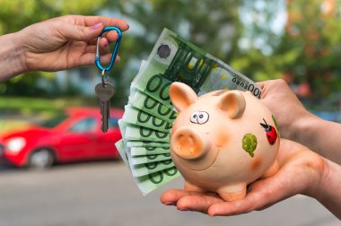 Salesman giving car key to a new car owner, who is paying last s