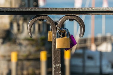 Love padlocks on a railing in the harbor on blurred lighthouse background