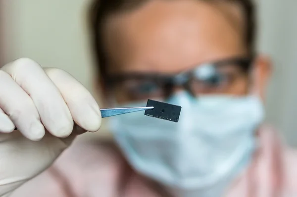 Scientist holding and examining damaged electrical chip — Stock Photo, Image