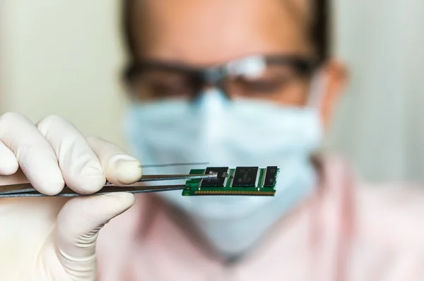 Scientifique tenant et examinant un composant électrique endommagé Images De Stock Libres De Droits