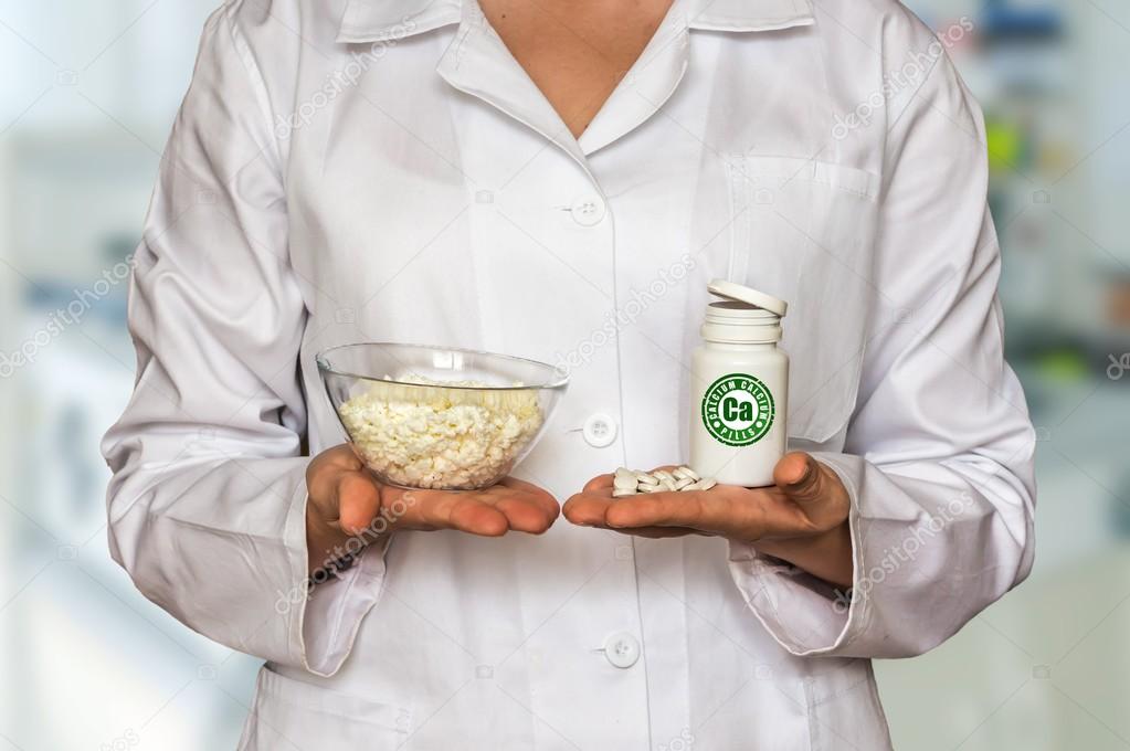 Young doctor holding curd and bottle of pills with vitamins and compare them