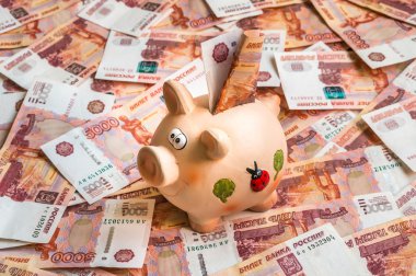 Piggy bank in a pile of russian five thousand banknotes
