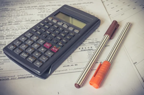 Calculator and pens on bank statement on the table — 스톡 사진