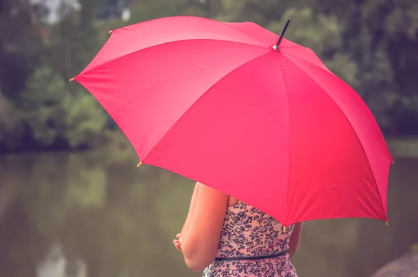 Mädchen mit rotem Regenschirm in Teichnähe — Stockfoto