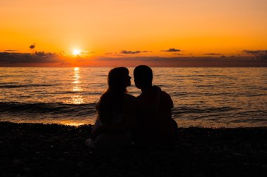 Genç bir romantik çift batımını silüeti
