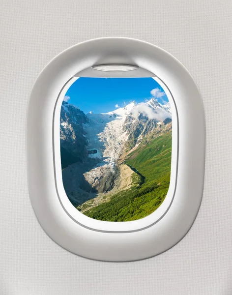 Blick aus dem Fenster eines Flugzeugs auf die Berge und den Gletscher — Stockfoto