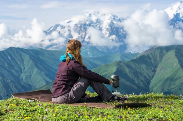 Young lady hiker preparing something to eat in the mountains — Stock Photo, Image