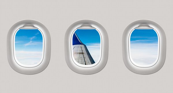 Looking out the windows of a plane to the aircraft wing and clou