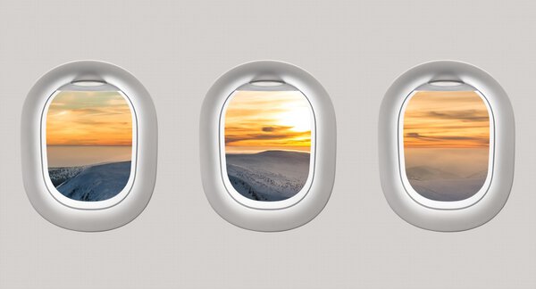 Looking out the windows of a plane to the winter mountains and s