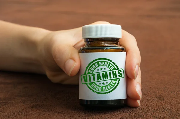 Человеческая рука держит бутылку таблеток с витаминами — стоковое фото
