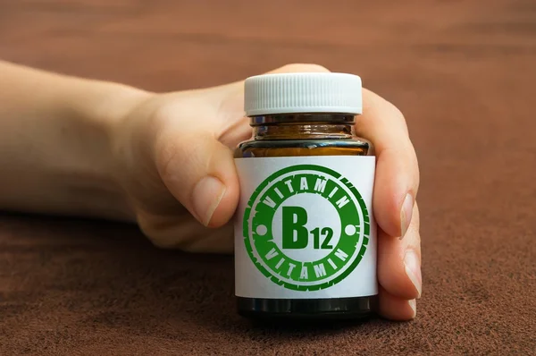 Main humaine tenant une bouteille de pilules avec de la vitamine B12 — Photo