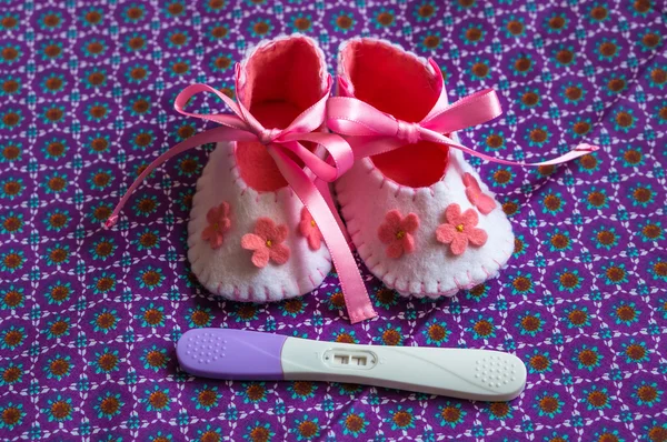Newborn baby girl booties and pregnancy test — Stock Photo, Image