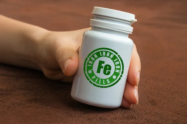 Mänskliga handen håller en flaska av piller med järn — Stockfoto