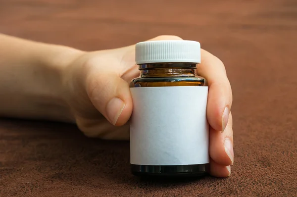 Mano humana sosteniendo una botella de pastillas — Foto de Stock