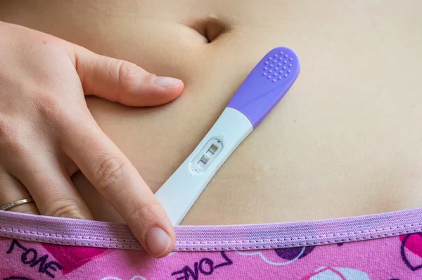 Positive pregnancy test on belly — Stock Photo, Image