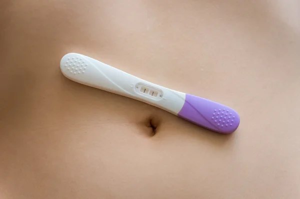 Positive pregnancy test on belly — Stock Photo, Image