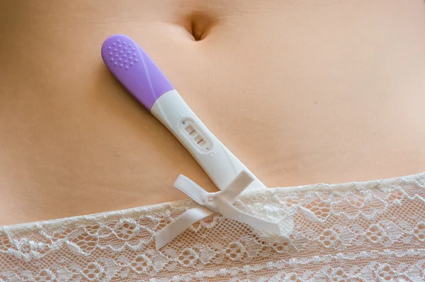 Positive pregnancy test on belly — Stock Photo, Image