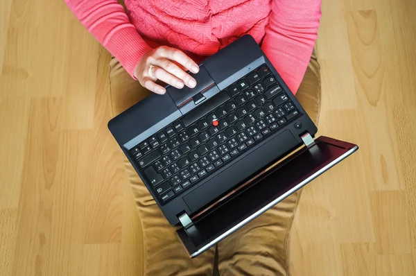 Молодий студент використовує ноутбук і сидить на дерев'яній підлозі — стокове фото