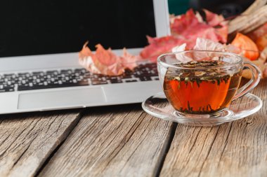 Cup of herbal tea on table with laptop