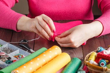 closeup of woman hands sewing pink hamdmade toy