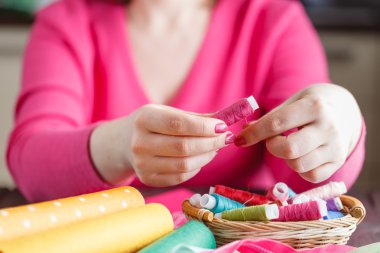 The woman is holding threads 