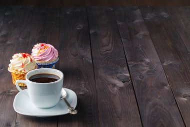 Cupcake and coffee on dark rustic table