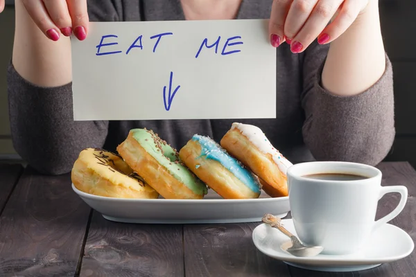 Woman take donuts and hold message eat me — Stock Photo, Image