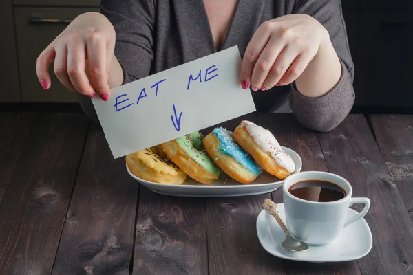 Woman take donuts and hold message eat me — Stock Photo, Image