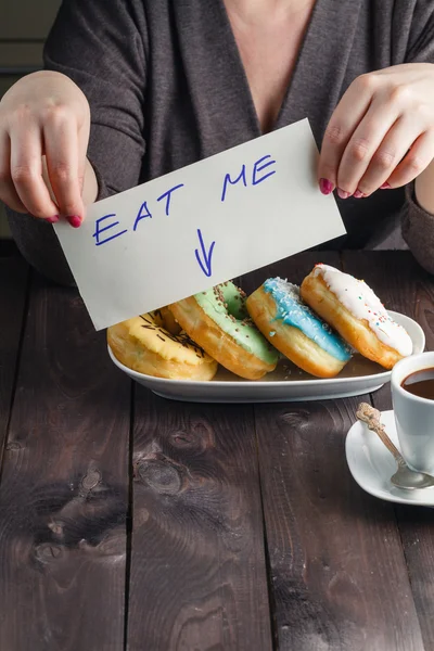 Woman take donuts and hold message eat me — Stock Photo, Image