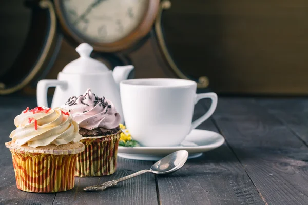 Cupcakes y taza de tra sobre fondo de madera oscura — Foto de Stock