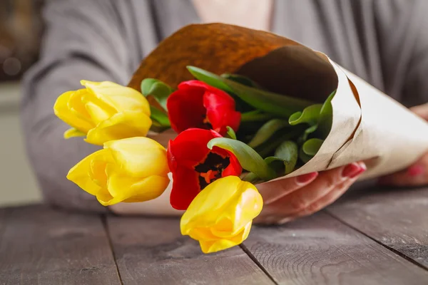 Mulher segurando tulipas em papel artesanal — Fotografia de Stock