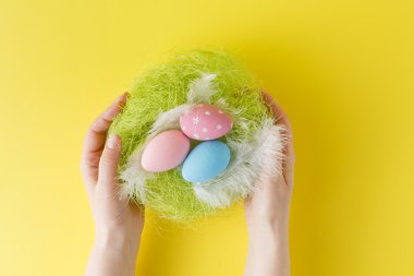 Modern boyalı Paskalya yortusu yumurta içinde küçük bir yuva holding eller