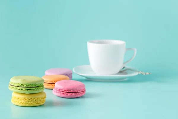Pastell gefärbte Makronen mit Kaffee auf Aquamarin-Hintergrund — Stockfoto