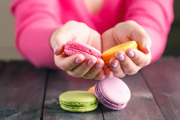 Macaroons colored in the hands of woman. French dessert. Close-u — Stock Photo, Image