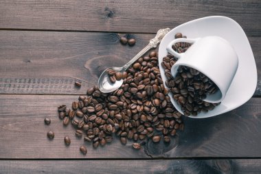 ahşap arka plan üzerine bir bardak kavrulmuş kahve çekirdeği