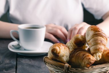 Sepet ve lezzetli taze kruvasanlar ve sıcak sabah fincan kahve