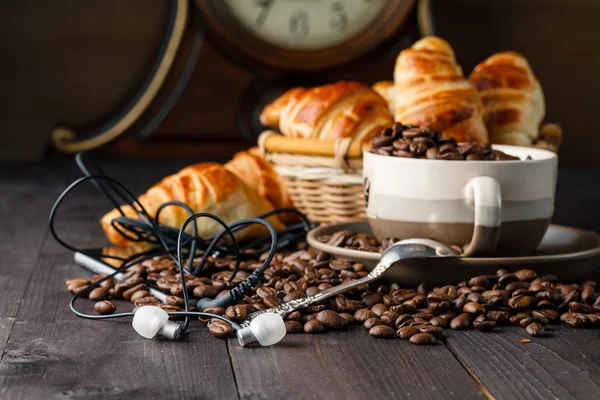 Tomar café y croissants con smartphone y auriculares — Foto de Stock