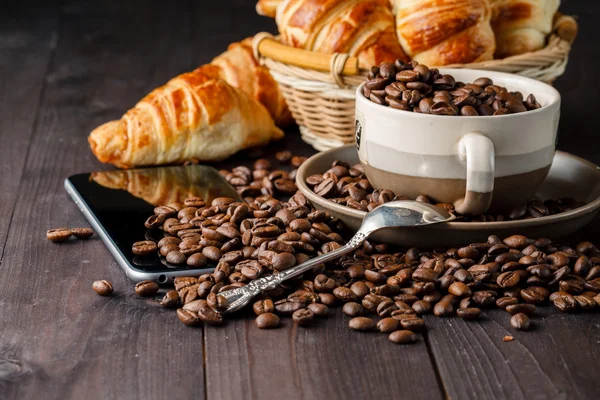 Tomar café y croissants con smartphone y auriculares — Foto de Stock