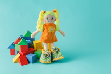 Düz arka plan üzerinde ahşap yapı taşları olan çocuk oyuncak bebek