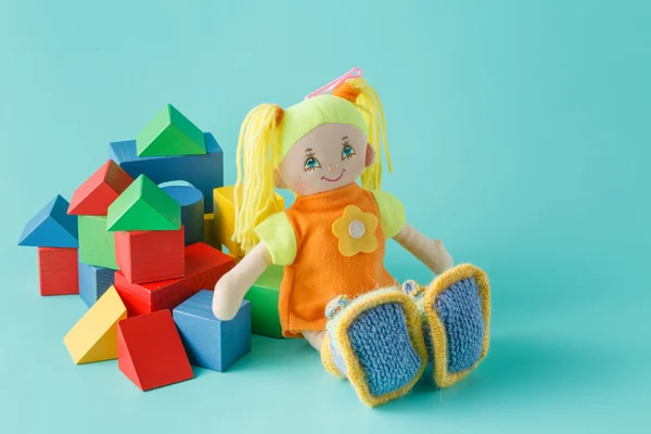 Muñeca de niño con bloques de construcción de madera sobre fondo liso —  Fotos de Stock