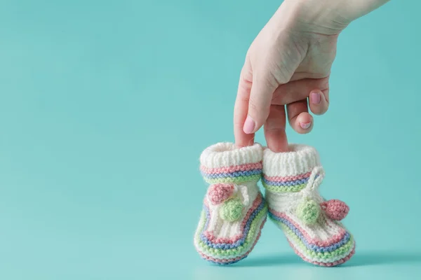 Mano femenina sostiene pequeños zapatos de bebé — Foto de Stock