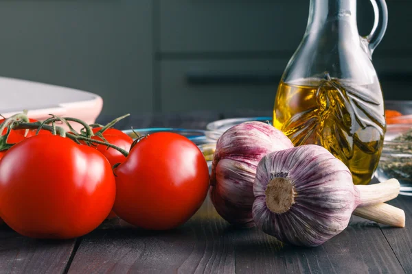 Tomaten en knoflook op houten zwarte tabelachtergrond — Stockfoto