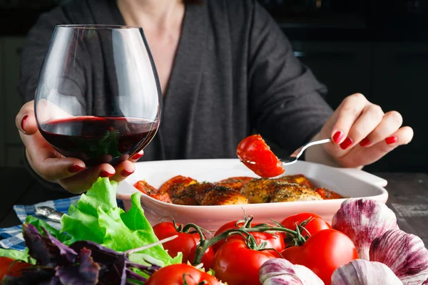 Vrouwelijke drink rode wijn en eten roiast kip — Stockfoto