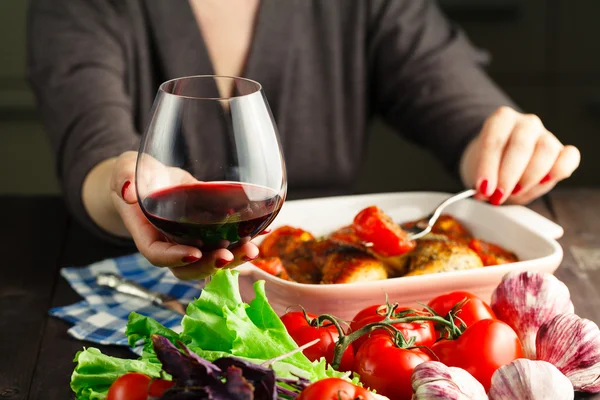Vrouwelijke drink rode wijn en eten roiast kip — Stockfoto