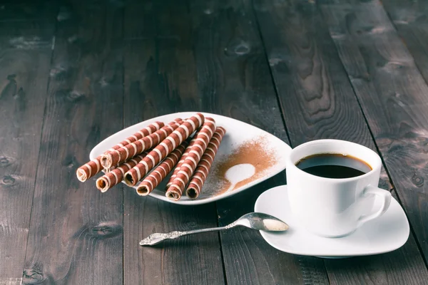 coffee and wafer rolls on a black background