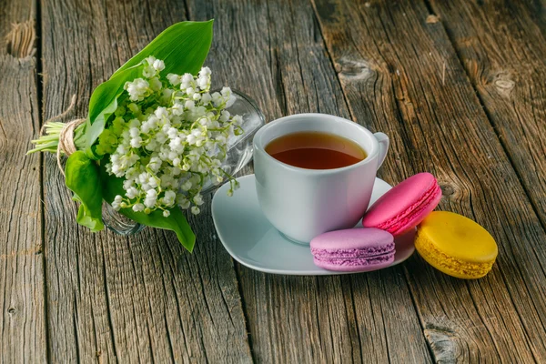 Deliciosos macarrones con taza de té en la mesa — Foto de Stock