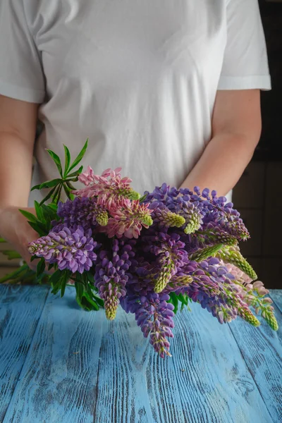 Bouquet of summer flowers in female hands against a wooden surfa — Stock Photo, Image